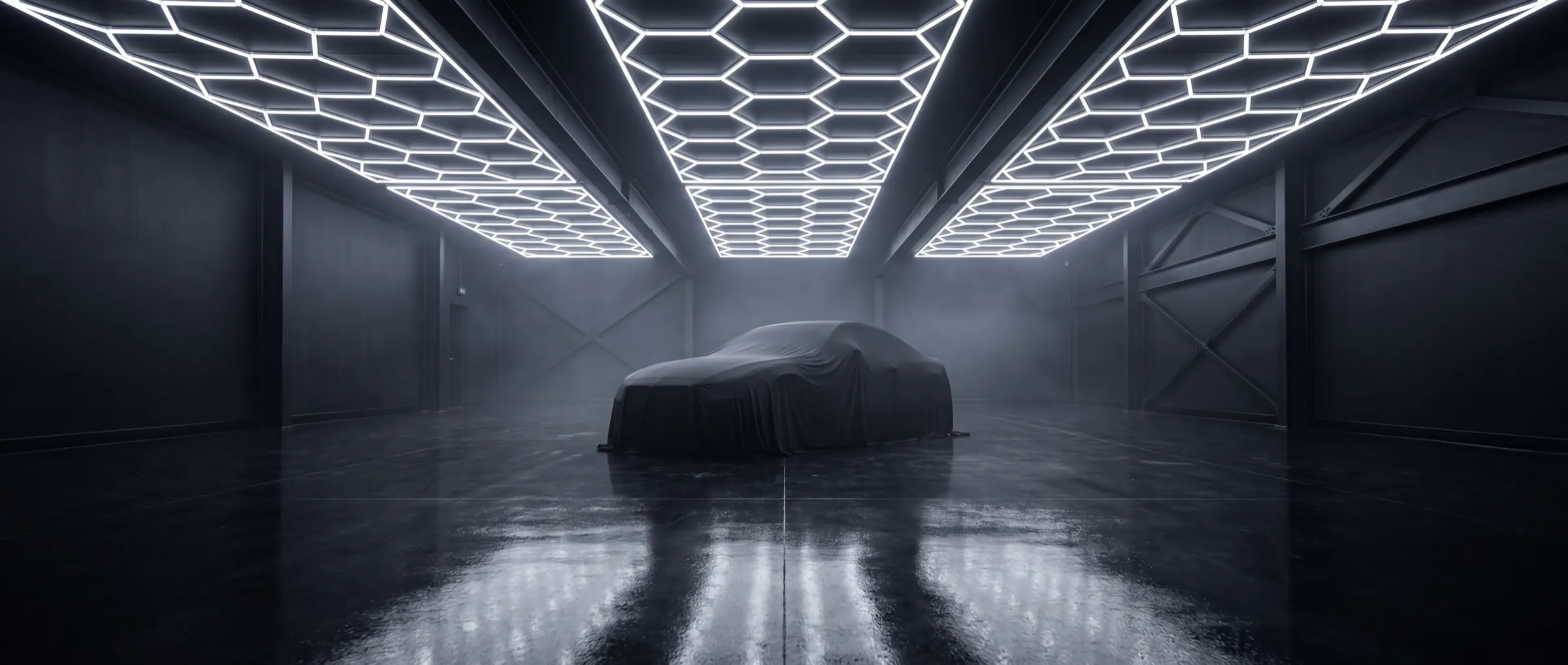 Covered exotic car in a climate-controlled storage hall under a hex LED ceiling array